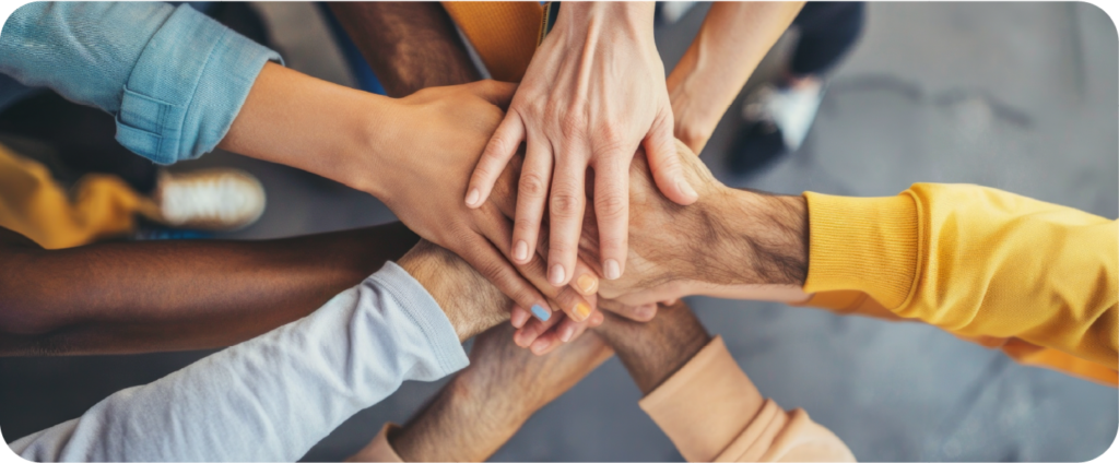 Team members stacking their hands together in a show of unity